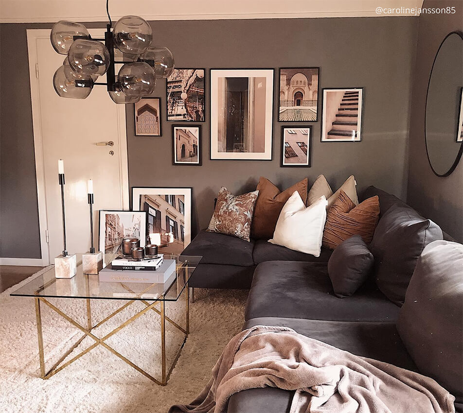 Sitting room in dark, earthy tones - grey velvet sofa, black frames, bubble lamp, round mirror